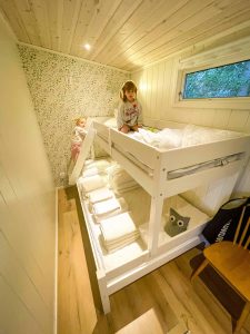 Two young girls in a small bedroom. One is sitting on the top bunk and another is climbing up the bed ladder. | Högbro Brukstuga | Sandviken Sweden | Destination Unknown