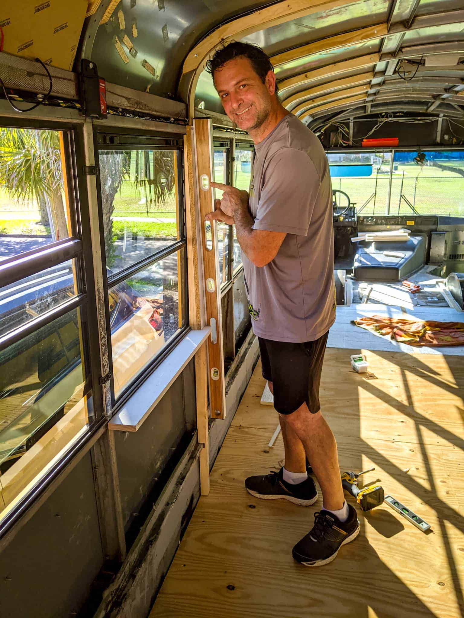 Eric using the level to during the wall furring strip installation. | what is a skoolie roof raise DESTINATION UNKNOWN