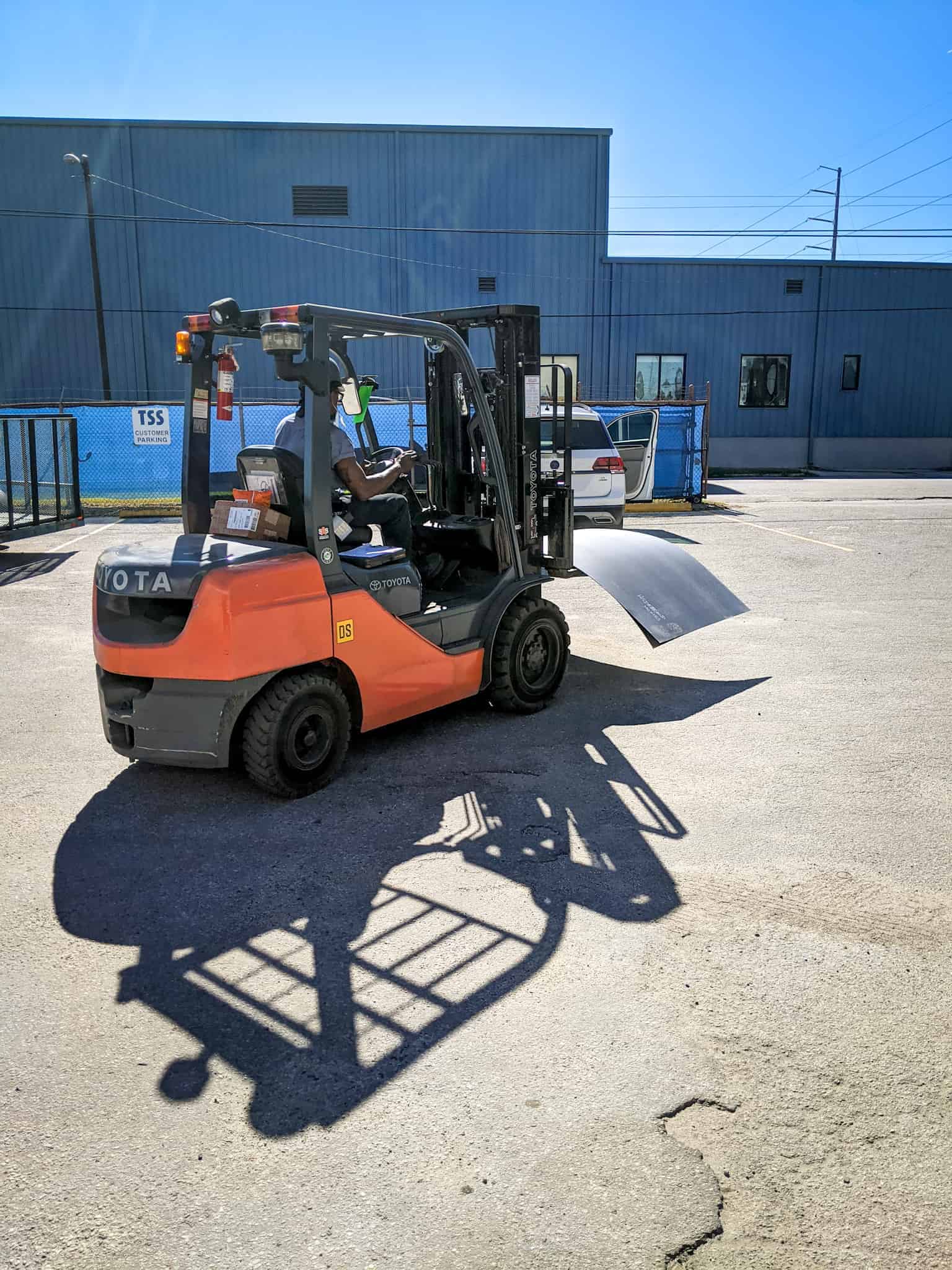 Orange and black forklift carrying sheet metal | what is a skoolie roof raise? | Destination Unknown