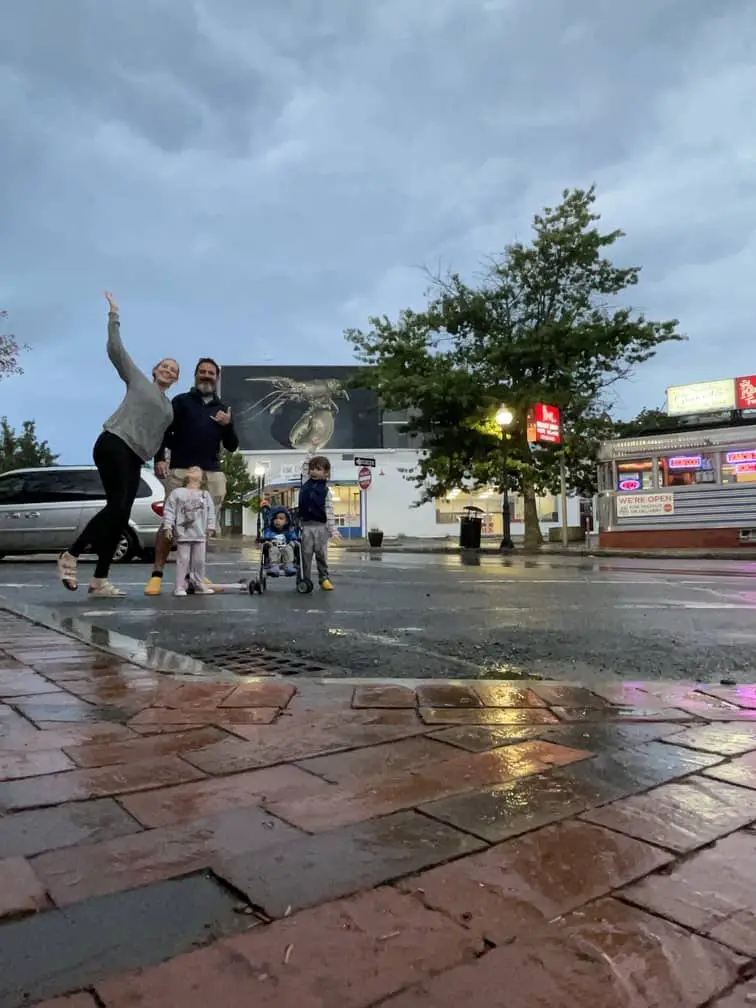 Photo of a mom, dad and three young children posing on a side walk on a rainy evening in Massachusetts.