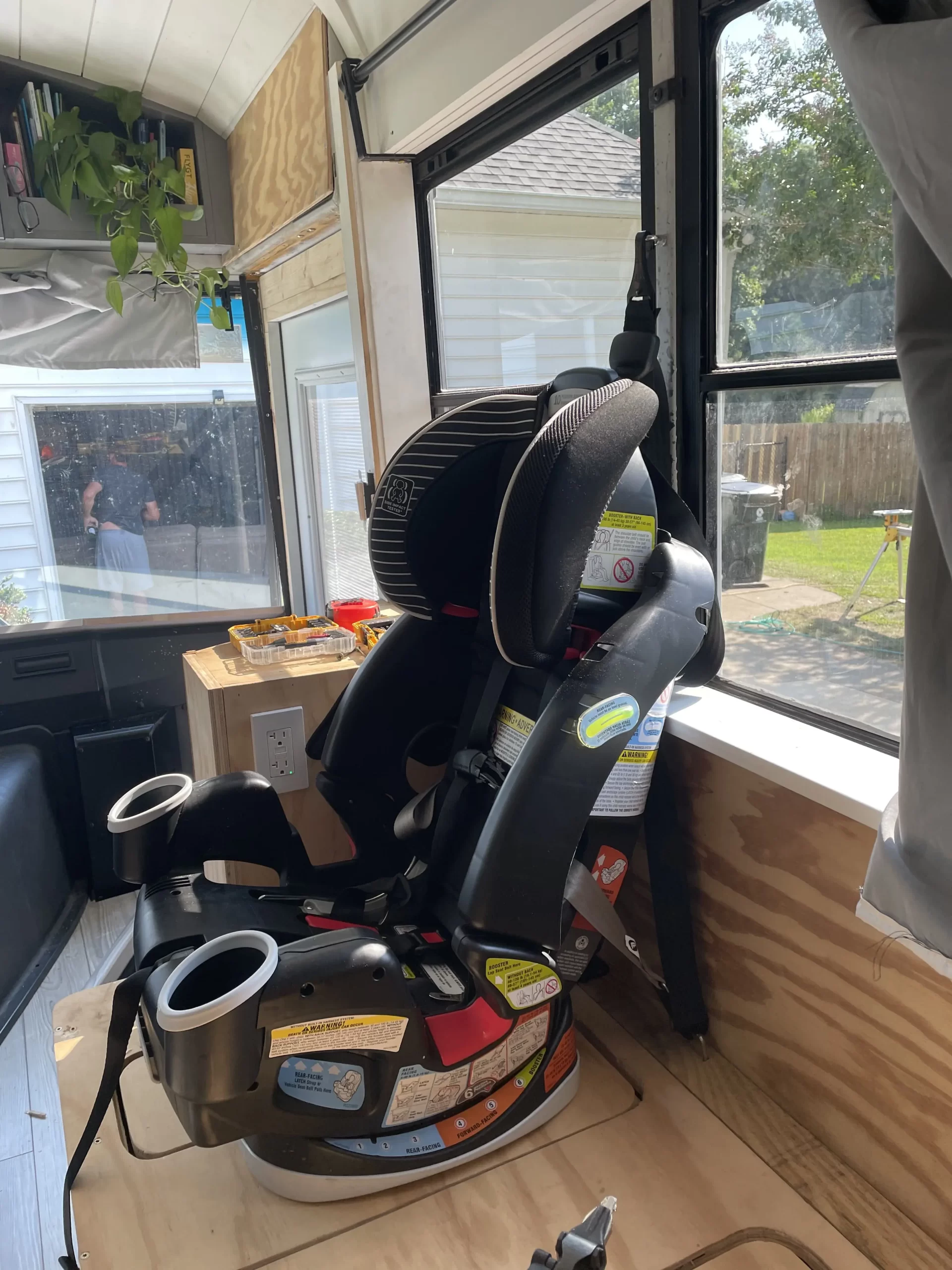 Car seat attached to mounting brackets in school bus conversion.