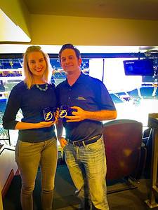 A man and a woman smiling and holding NHL Tampa Bay Lightning Coffee Mugs. They are standing in a private box at the Amalie Arena while the hockey team plays.